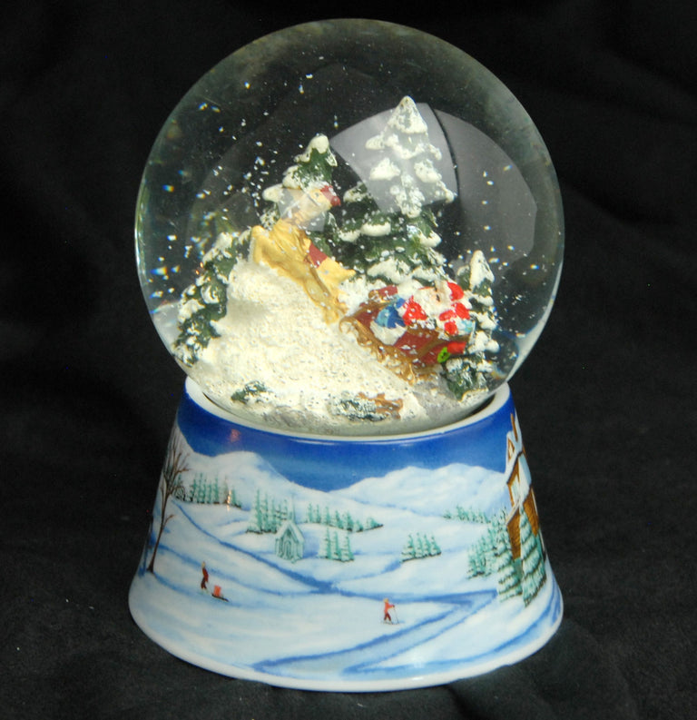 Schneekugel Santa im Schlitten auf Sockel Winterlandschaft mittelblau mit Spieluhr 10 cm Durchmesser - Schneekugelhaus